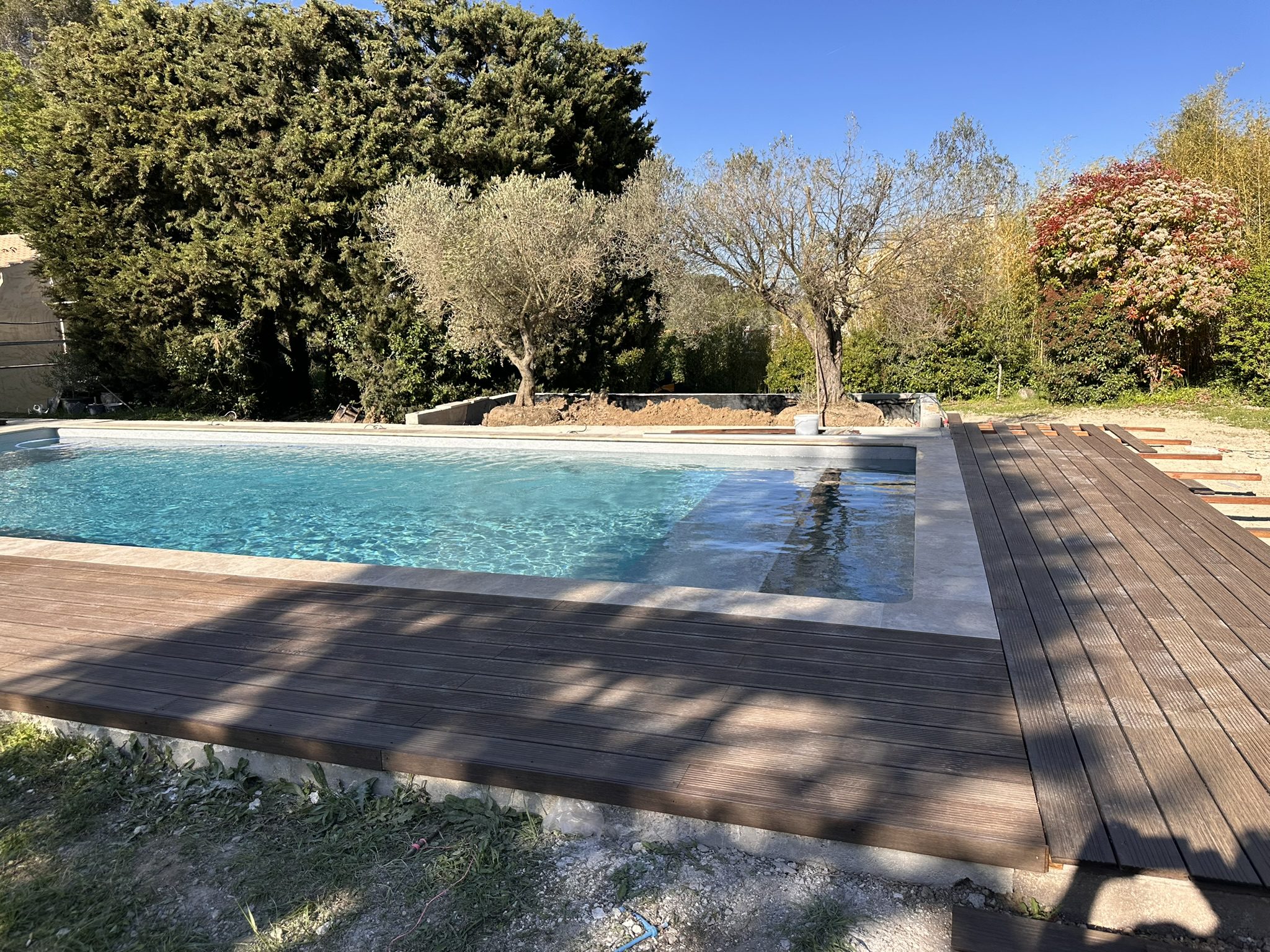Travaux de construction et rénovation d'une piscine avec remplacement des margelles et aménagement de la plage en bois, réalisés par Entreprise Pellegrini à Bouc-Bel-Air.
